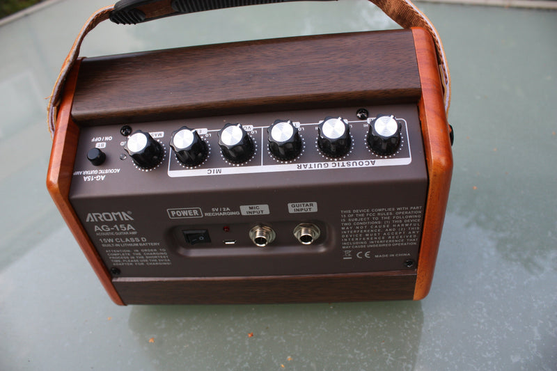 Aroma AG-15 rechargeable battery acoustic guitar amp. 15W output, woodgrain cabinet with tweed fretcloth and carry strap.