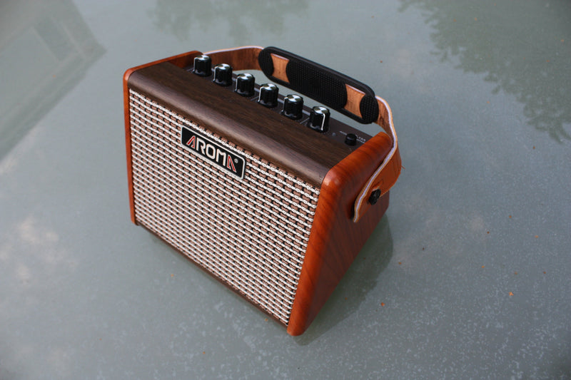 Aroma AG-15 rechargeable battery acoustic guitar amp. 15W output, woodgrain cabinet with tweed fretcloth and carry strap.